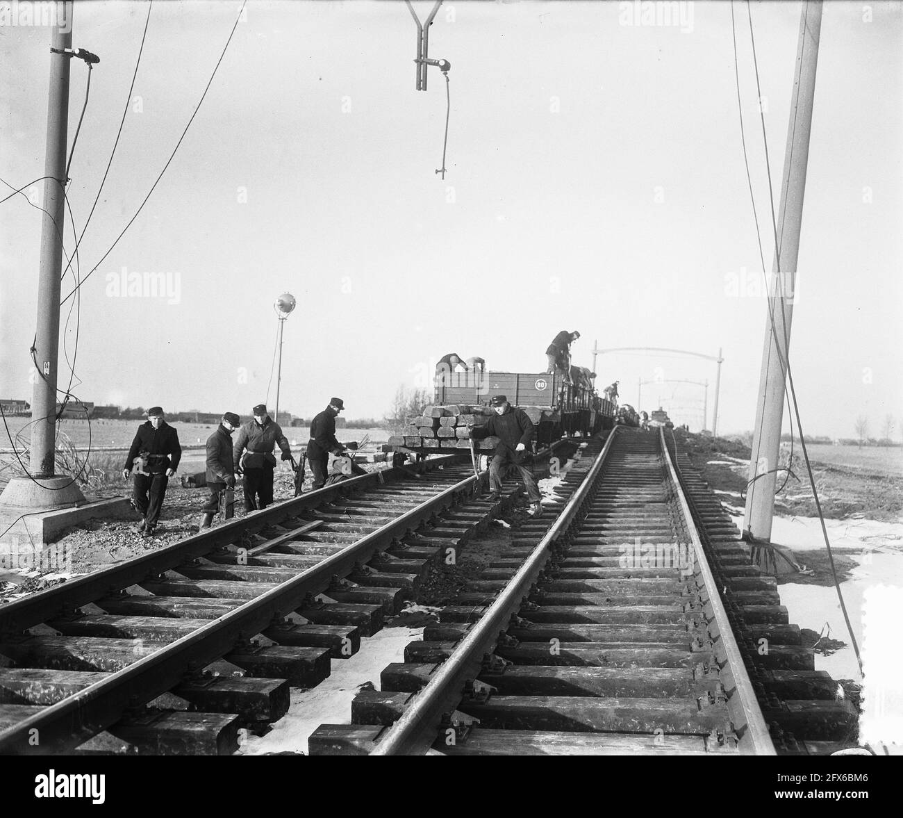 Eisenbahnsanierung Moerdijk [Watersnood 1953] die Arbeiten an der Eisenbahn zwischen Dordrecht über die Moerdijk-Brücke nach Brabant sind fieberhaft. Mit Zügen werden Sand und Bilge eingefahren und vor Ort in der Nähe der Moerdijk-Brücke wird der Sand direkt gegossen, so dass die Schienen, die jetzt keine Stütze haben, sondern einfach hängen, wieder etwas Boden fühlen. Der gesamte Bahndamm ist über eine große Strecke von rund 2.50 Metern gesunken. Die erste Voraussetzung ist, diesen Eisenbahnabschnitt zu erhöhen. Man hofft, in 6 Wochen bereit zu sein, 10. Februar 1953, Erholung, Überschwemmungen, Eisenbahnen, Züge, Niederlande, 20. Jahrhundert Stockfoto