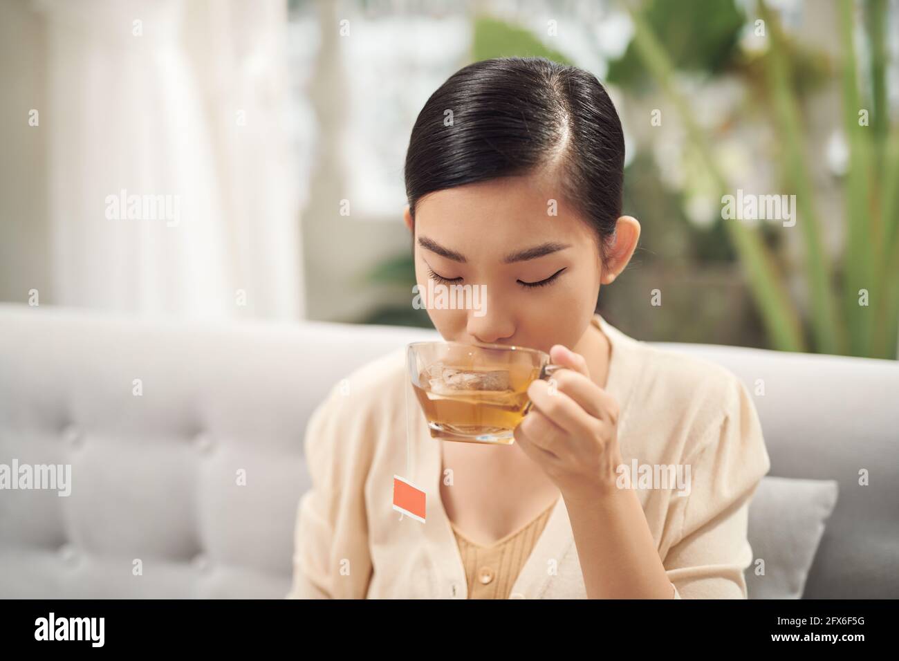Junge attraktive asiatische Frau, die Tee trinken Stockfoto