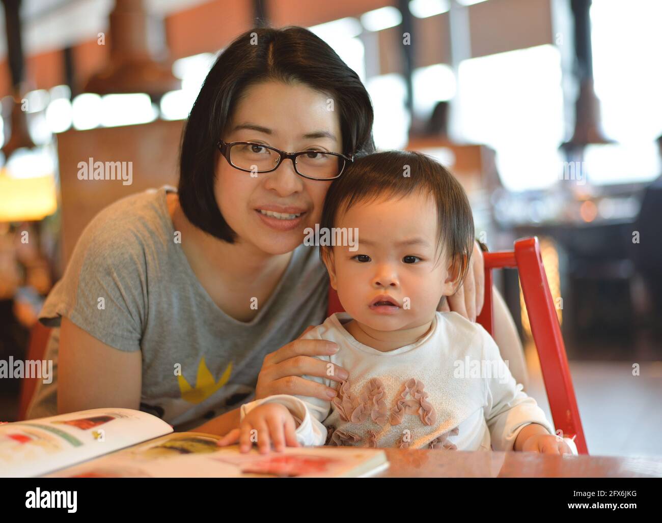 Schöne asiatische Mutter und Kleinkind Mädchen zusammen in einem Restaurant, Frau mit Brille. Stockfoto