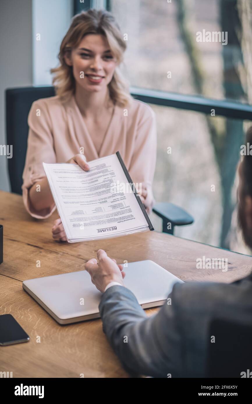 Junge Frau Chef gibt Dokumente an Mann in Anzug Stockfoto