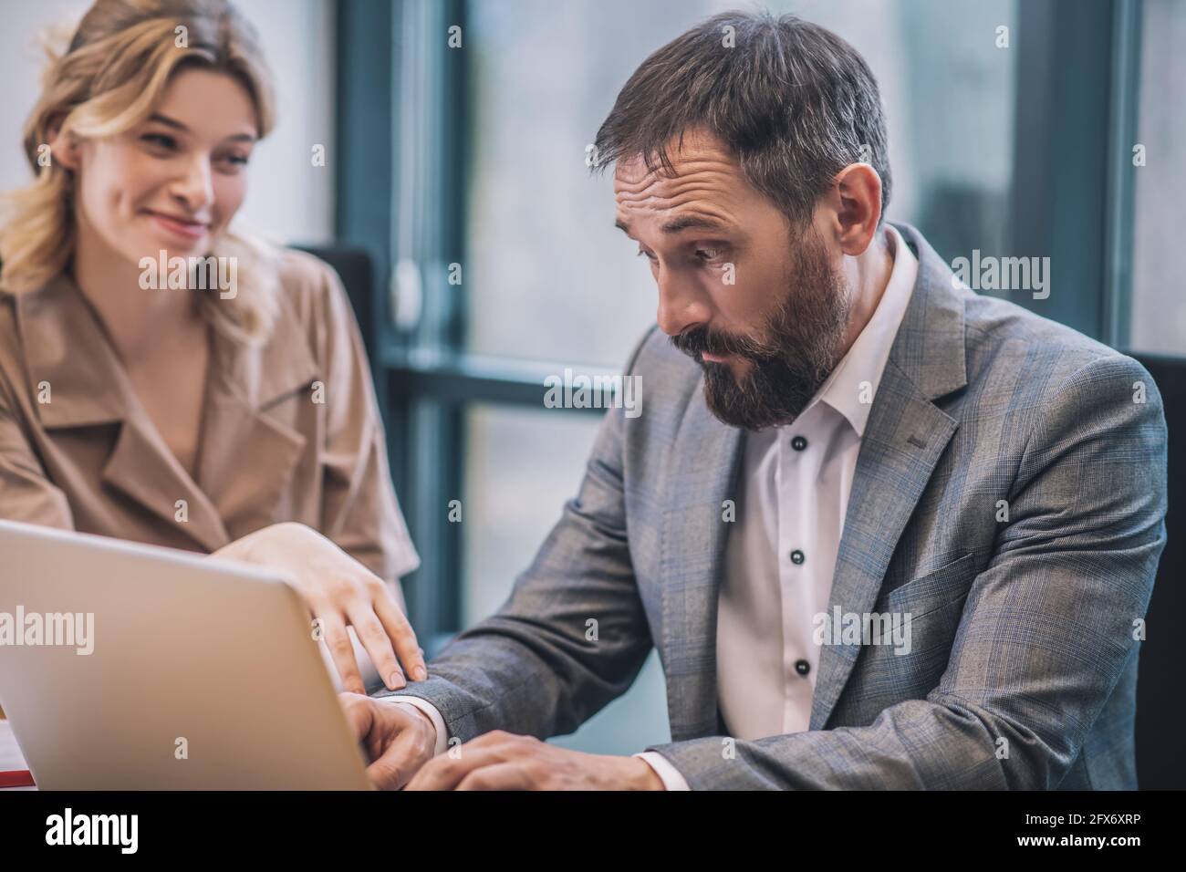 Überraschte den Mann, der am Laptop arbeitete und einen Angestellten flirtet Stockfoto