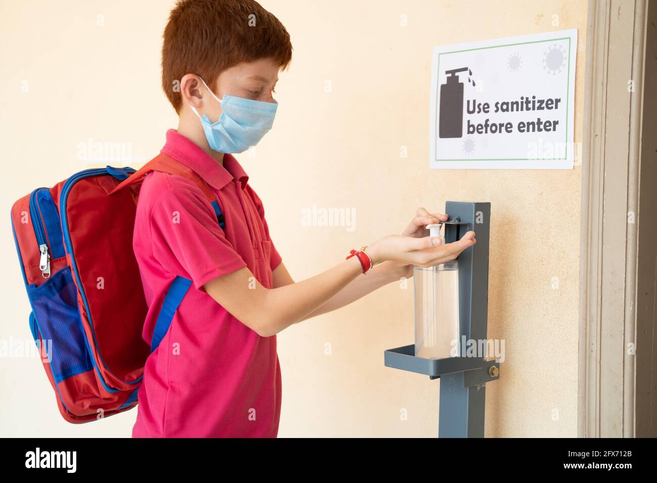Konzentrieren Sie sich auf Desinfektionsmittel, ein Kind mit medizinischer Maske und Handdesinfektionsmittel vor dem Betreten des Klassenzimmers – Konzept der Rückkehr zur Schule oder Schule mit Coronavirus Stockfoto