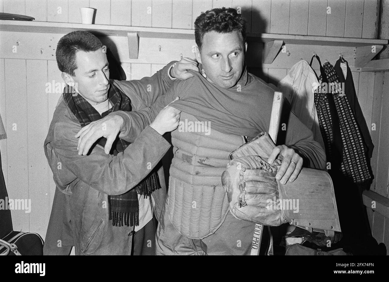 Eishockey in Jaap Edenbaan die Amsteltijgers gegen die Rotterdammers 5-11, der Rotterdamer Torwart R. Koopmans wird in seinem Geschirr von Mr. De Bruin, 20. Januar 1964, Eishockey, Goalies, Niederlande, Presseagentur des 20. Jahrhunderts, Foto, Nachrichten zum erinnern, Dokumentarfilm, historische Fotografie 1945-1990, visuelle Geschichten, Menschliche Geschichte des zwanzigsten Jahrhunderts, Momente in der Zeit festzuhalten Stockfoto