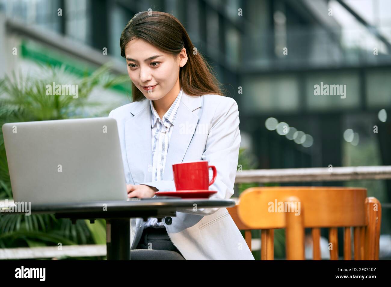 Junge asiatische Geschäftsfrau, die mit einem Laptop im Café im Freien arbeitet Computer Stockfoto