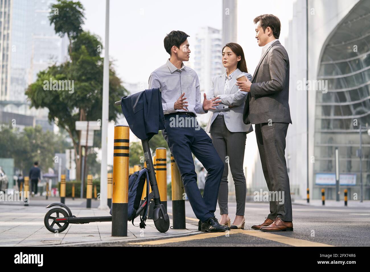 Drei asiatische Geschäftsleute unterhalten sich auf der Straße in der Innenstadt von Moderne Stadt Stockfoto