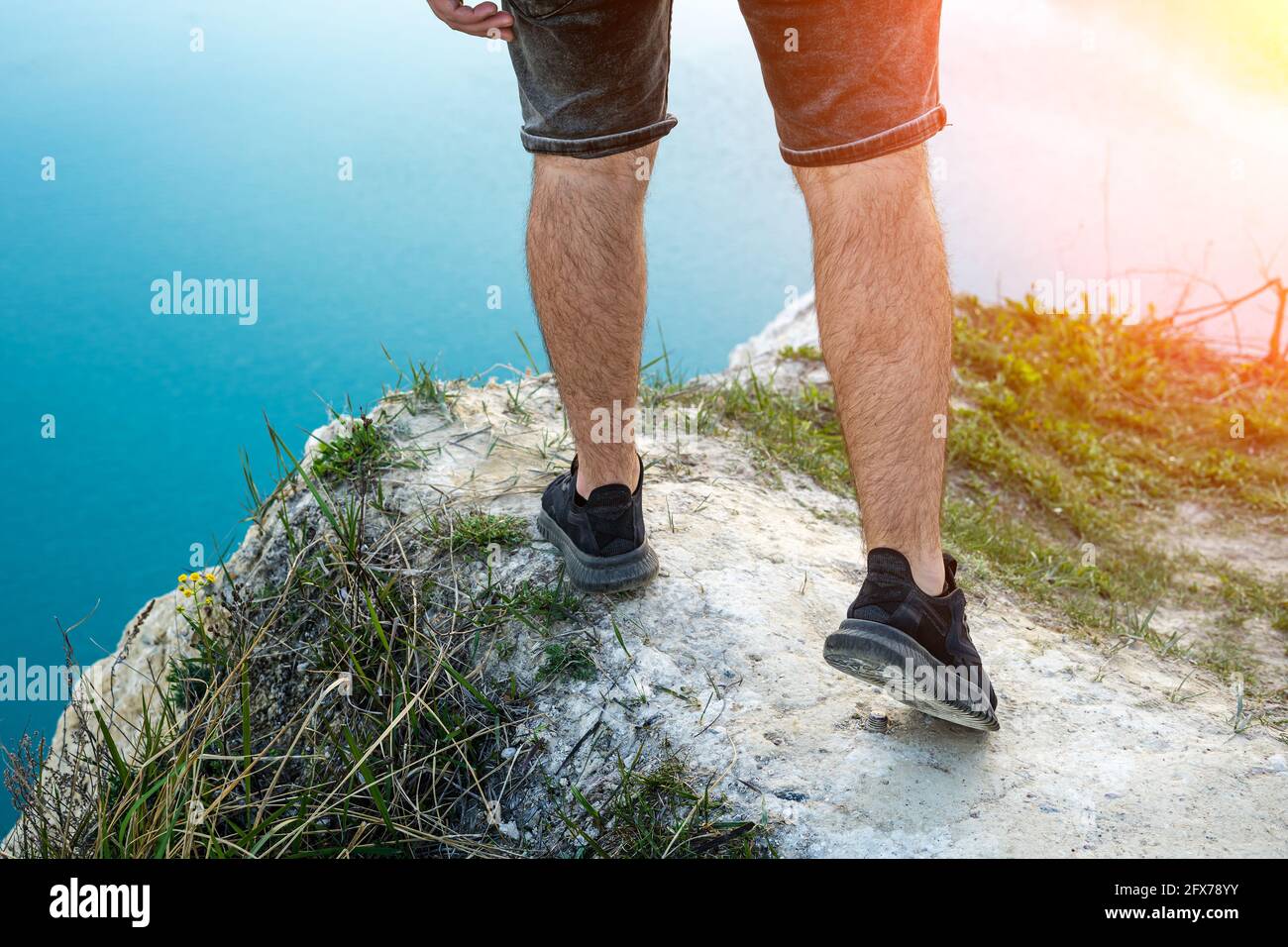 Typ in Shorts am Rand einer Klippe, die Beine aus der Nähe Stockfotografie  - Alamy