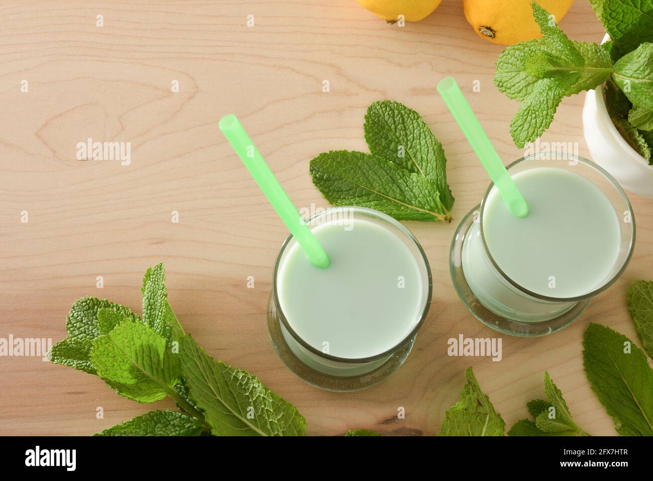 Milchshake mit Minze auf Holztisch und Minzblättern. Draufsicht. Stockfoto
