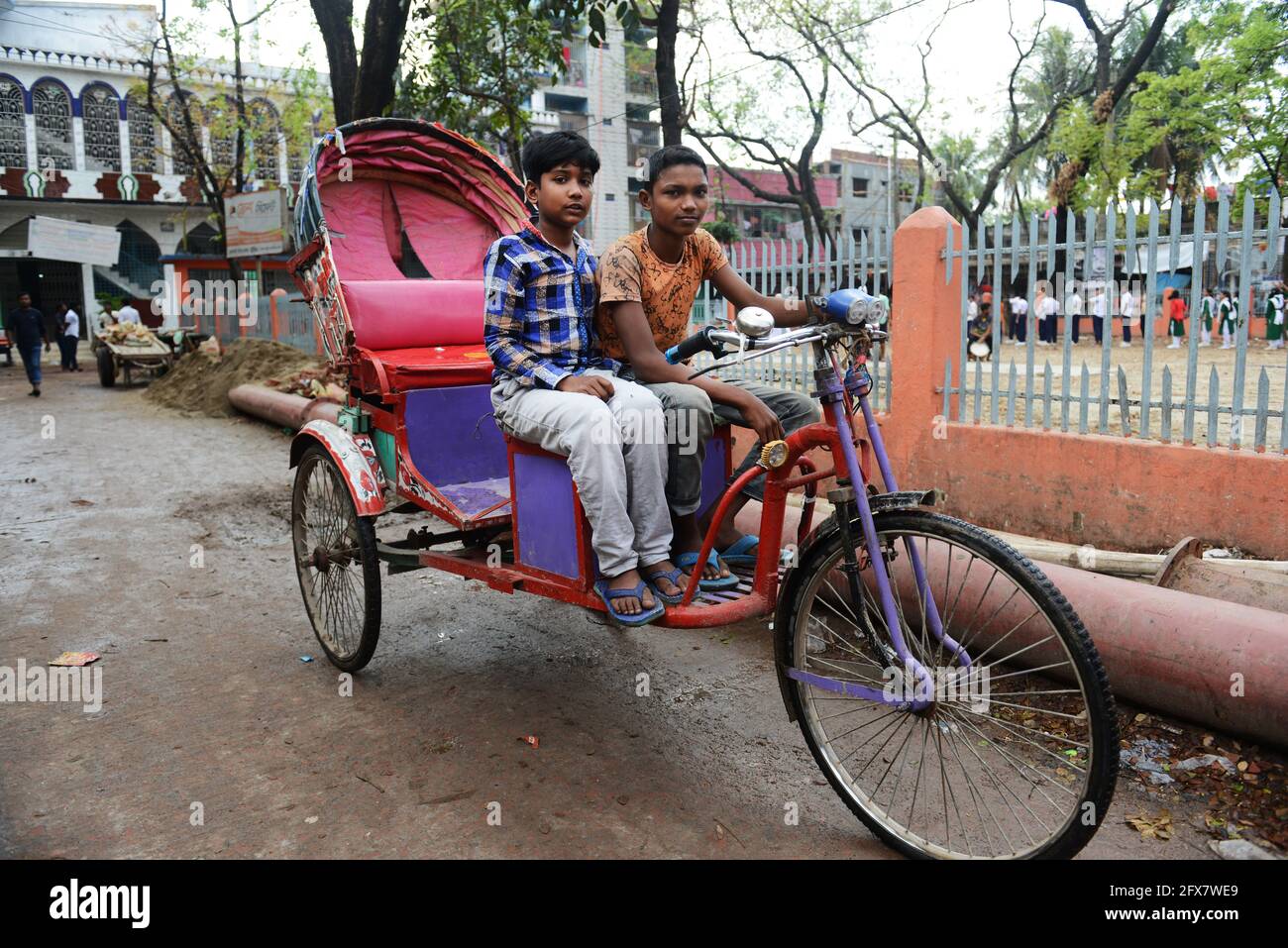 Bangladeschische Jungen sitzen auf einer Fahrrad-Rikscha in Dhaka, Bangladesch. Stockfoto