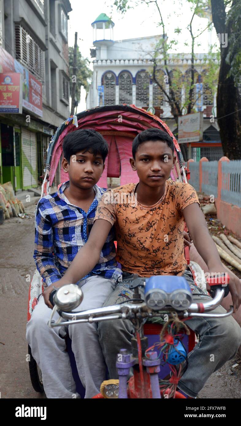 Bangladeschische Jungen sitzen auf einer Fahrrad-Rikscha in Dhaka, Bangladesch. Stockfoto