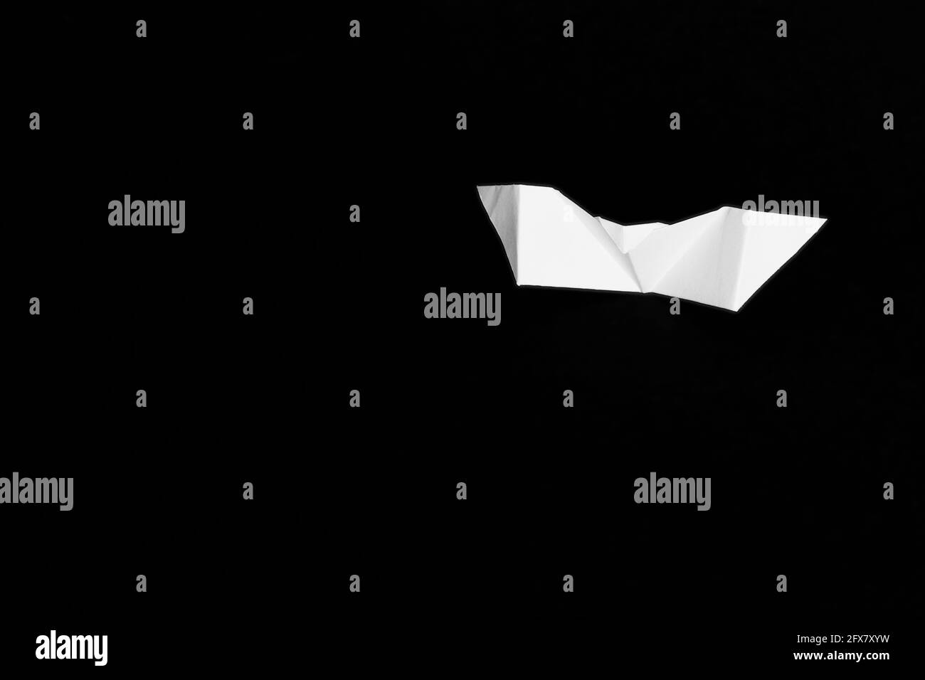 Weiße Origami-Fledermaus isoliert auf schwarzem Hintergrund. Es gibt Platz für Text oder Logos. Stockfoto