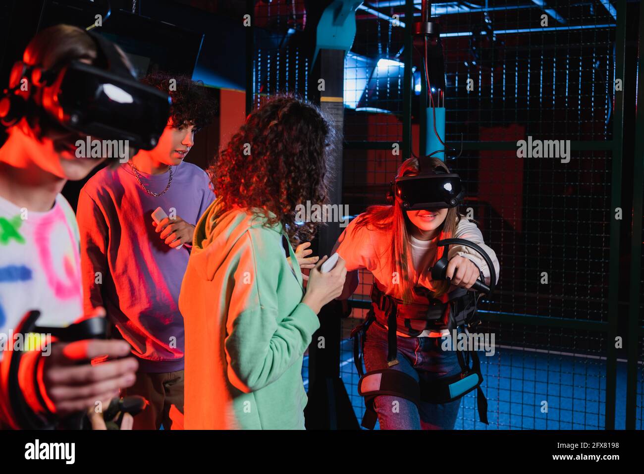 Teenager-Mädchen in Headset-Gaming in der VR-Spielzone in der Nähe Interracial Freunde Stockfoto