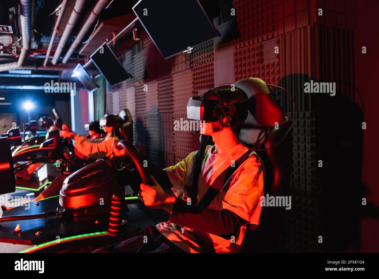 Teenager-Gamer in vr-Headsets Rennen auf Auto-Simulatoren in Wiedergabebereich Stockfoto