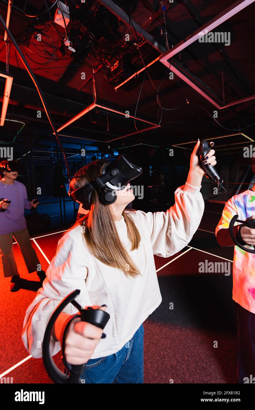 Teenager-Mädchen spielen im VR-Headset im Spielzimmer in der Nähe Freunde Stockfoto