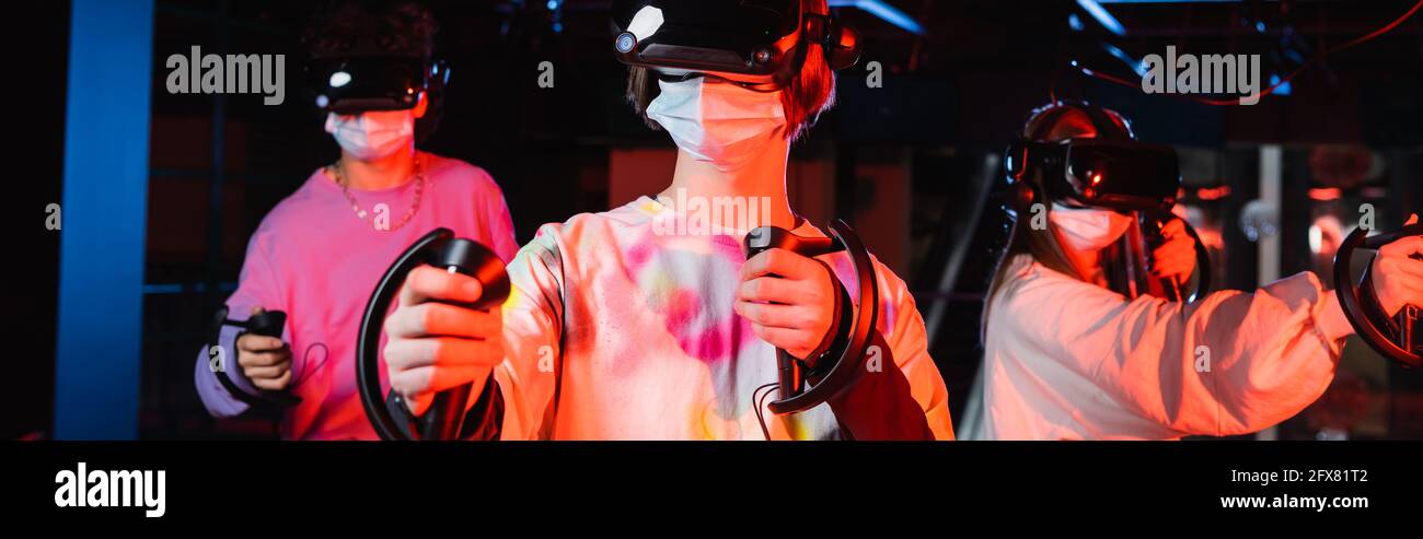 Teenager-Gamer mit VR-Headsets und Schutzmasken für Spiele in VR-Spielzone, Banner Stockfoto