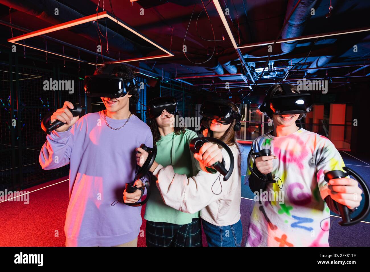 Aufgeregte multiethnische Teenager-Freunde in vr-Headsets spielen im Spiel Zimmer Stockfoto