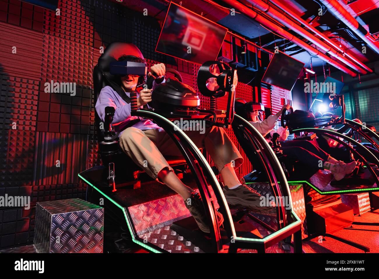 Teenager-Freunde spielen in Autorennen Simulatoren in vr spielen Zone Stockfoto