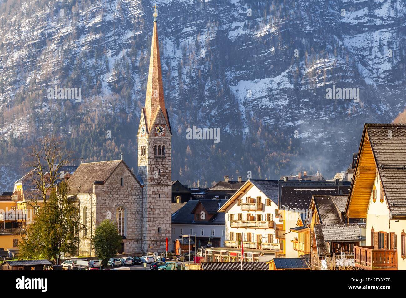 Blick auf die schöne Hallstatt berühmte Kirche während des Morgens Sonnenaufgang in Früher Frühling mit Bergketten bedeckt mit etwas Schnee in Hintergrund Stockfoto