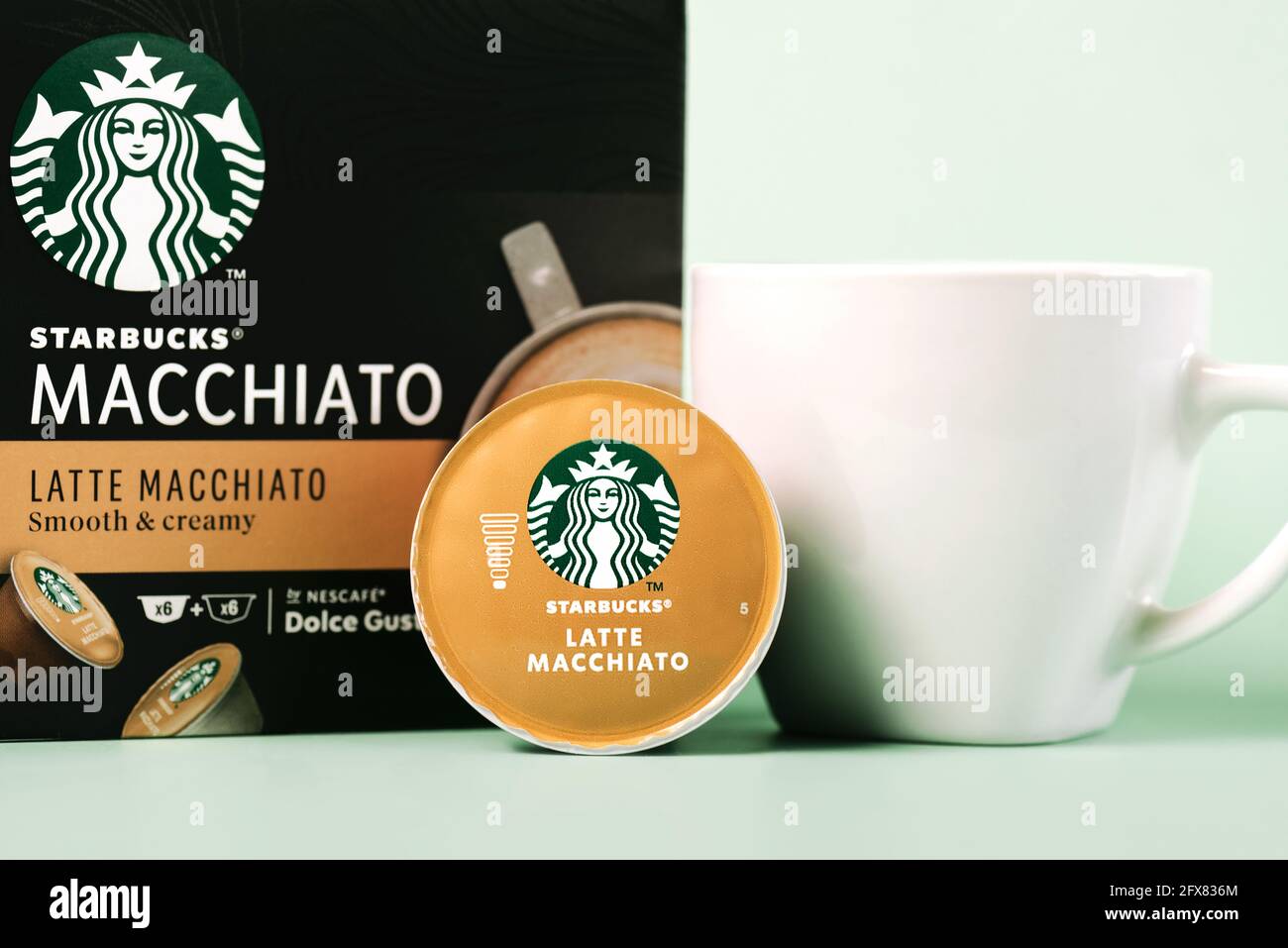 Starbucks Latte Macchiato Kaffeekapseln Box neben weißer Tasse Kaffee und Kapsel Latte Macchiato auf grünem Hintergrund Stockfoto