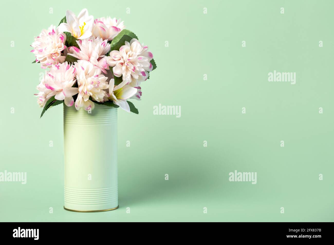 Blumen in einer MetallDose mit Kopierraum auf einem Grüner Hintergrund Stockfoto
