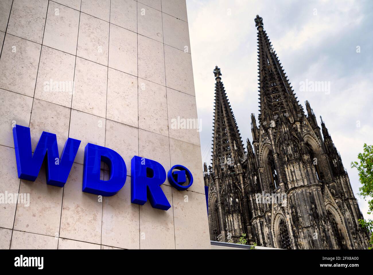 Köln, Deutschland - 23. Mai 2021: Logo auf der Fassade des WDR-Rundfunkgebäudes, im Hintergrund das Kölner Domlogo auf der Fassade des Th Stockfoto