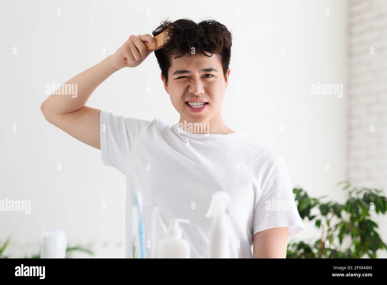 Asian gut aussehend junger Mann in weißem T-Shirt kombiniert mit Bürste Stockfoto