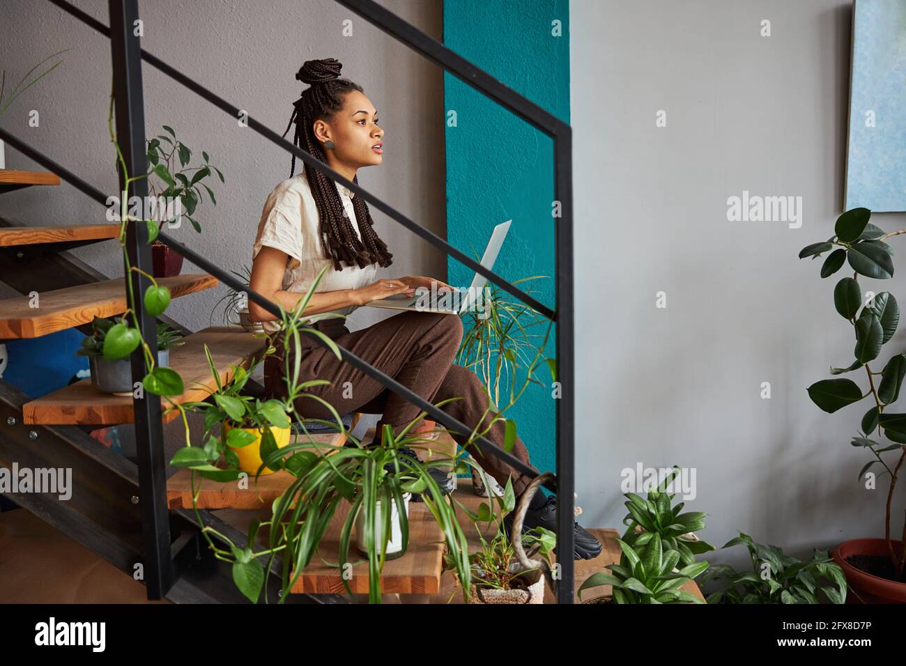 Nachdenkliche Frau mit einem Gadget auf der Treppe Stockfoto