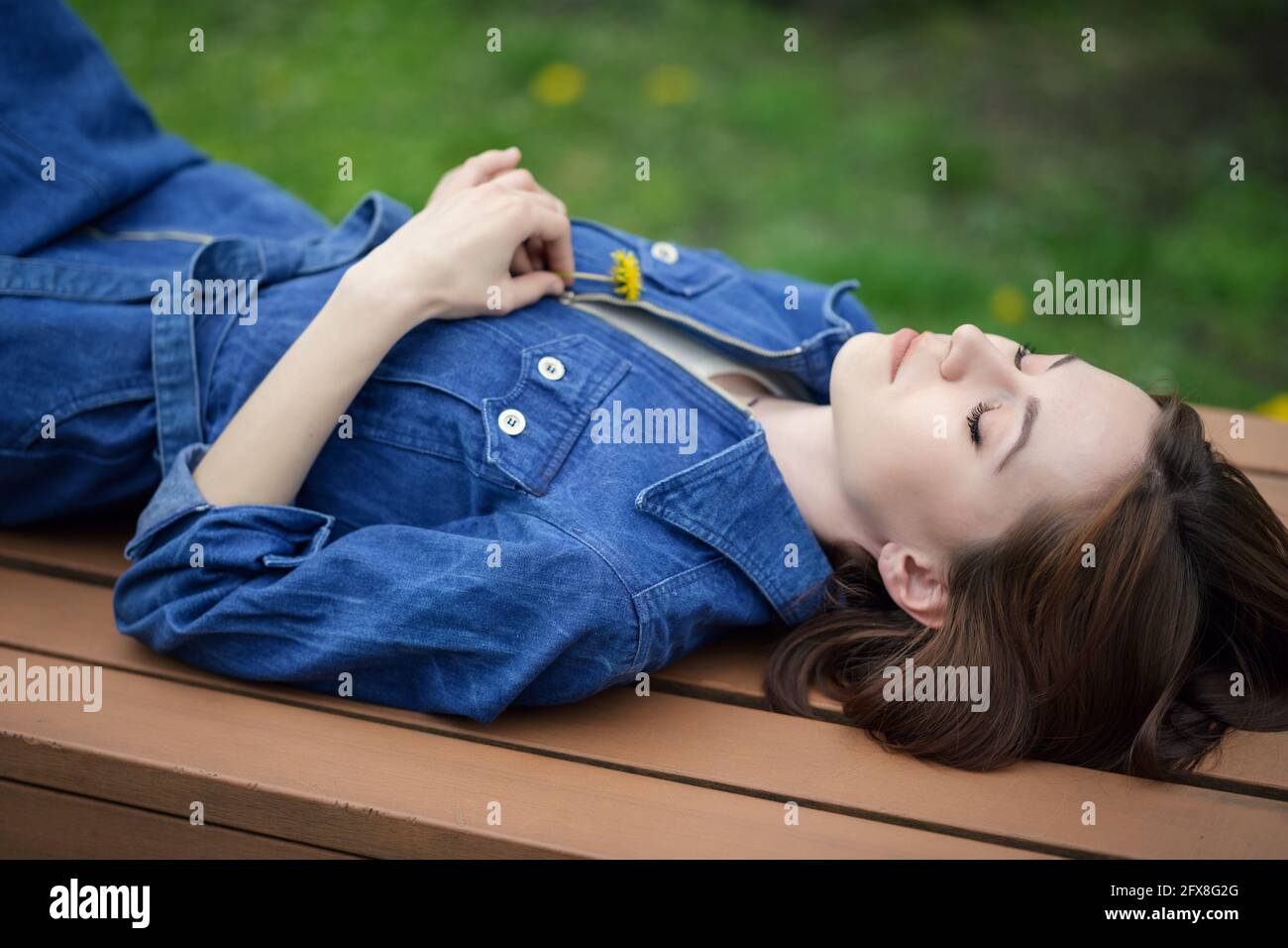 Porträt einer schönen ruhigen Frau. Sie liegt auf einer Parkbank. Stockfoto
