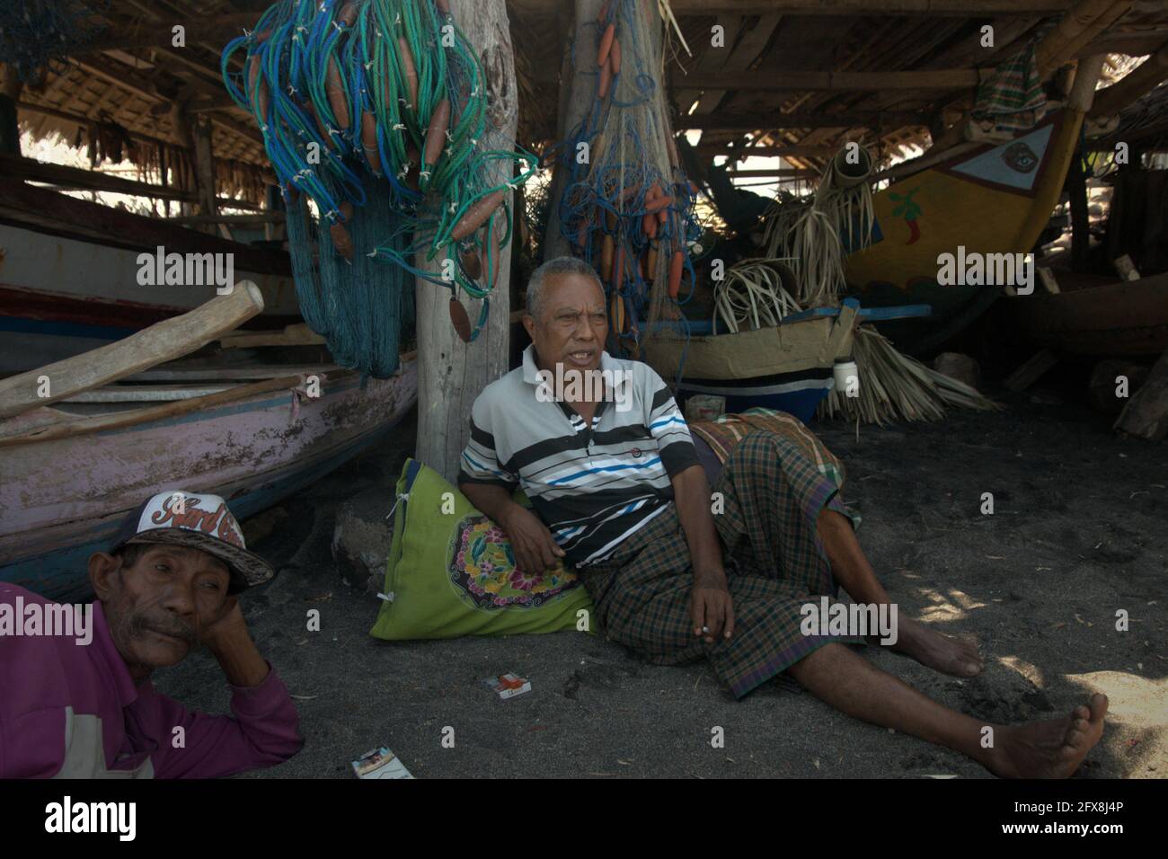 Männer, die Freizeit in einer Hütte haben, in der Boote und Fanggeräte im Dorf Lamalera, Lembata, Ost-Nusa Tenggara, Indonesien, gelagert werden. Stockfoto