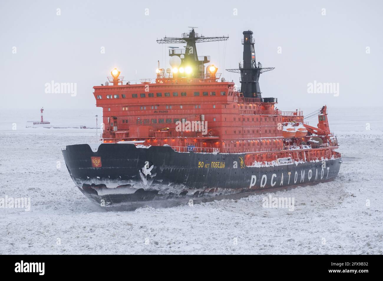 Sabetta, Region Tjumen, Russland - 4. April 2021: Der 50 ließ Pobedy Eisbrecher zieht in Eis. Bewölkt, leichter Schnee fällt. Stockfoto