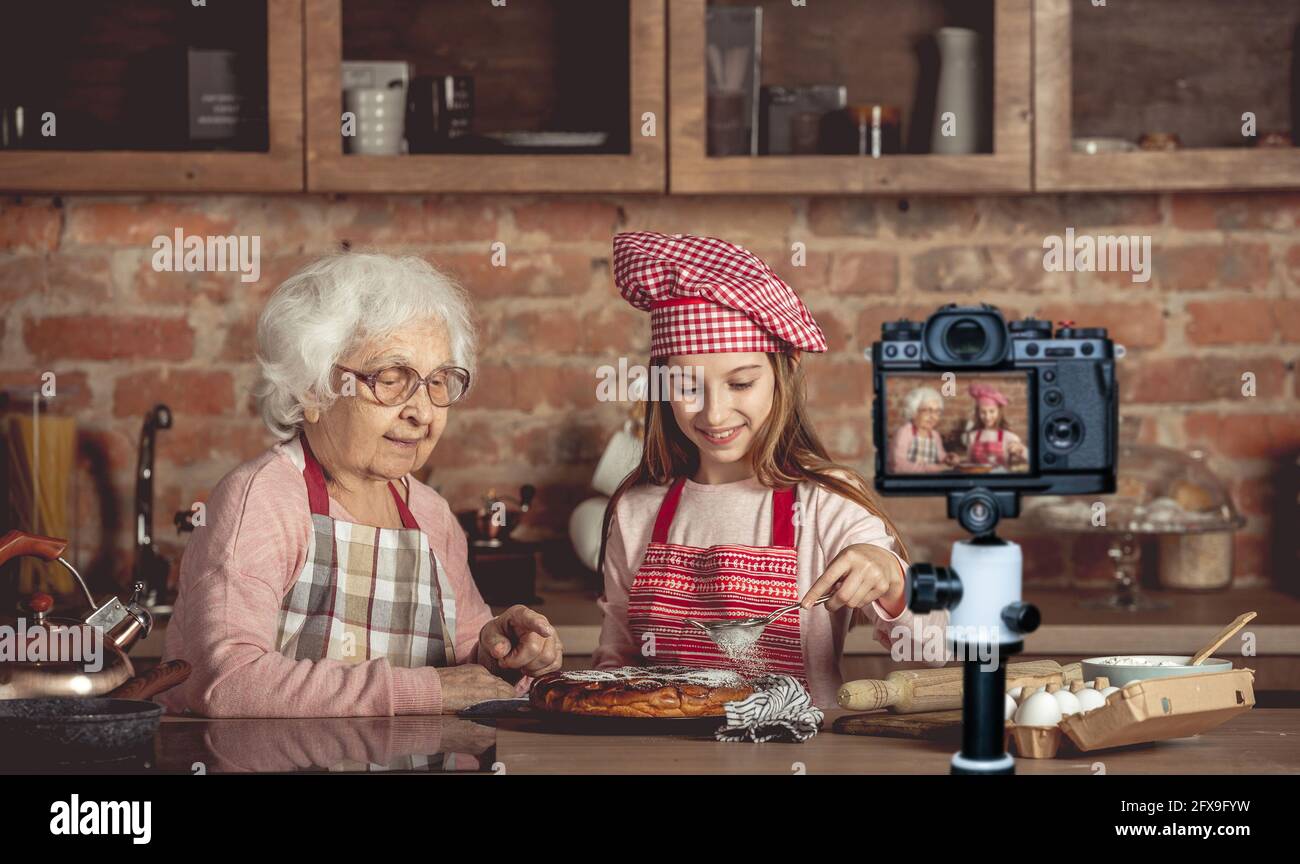 Oma hilft ihrer Enkelin mit hausgemachtem Kuchen Stockfoto