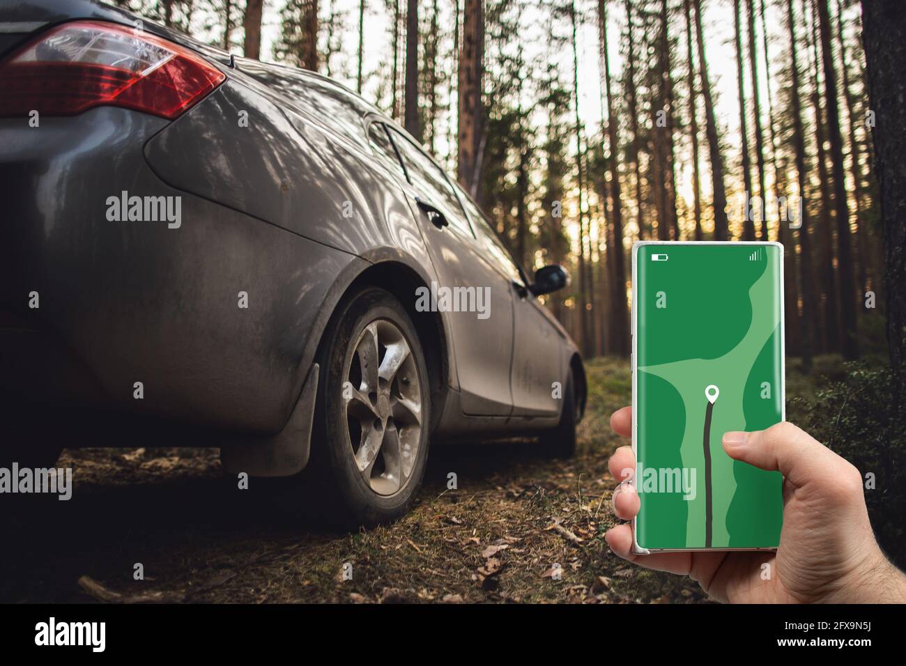 Das Konzept der Navigation auf Karten - ein Mobiltelefon mit gps-Navigator in der Hand und ein Auto im Wald in einer Sackgasse auf einer Waldstraße. Stockfoto