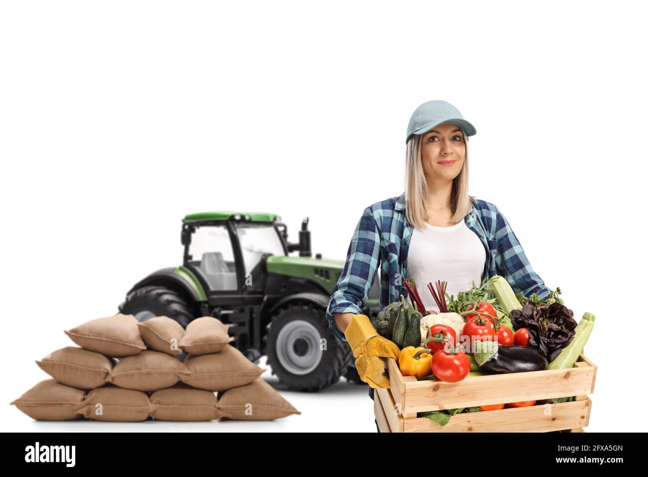 Frau mit einer Kiste Gemüse und einem Traktor isoliert Auf weißem Hintergrund Stockfoto