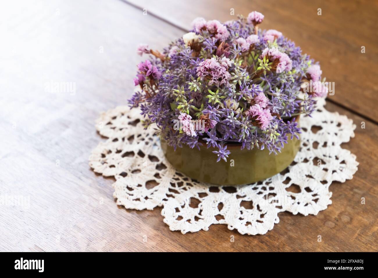 Runde Vase mit Blumenstrauß stehen auf einem Holzschreibtisch, Nahaufnahme Foto mit selektivem weichen Fokus Stockfoto