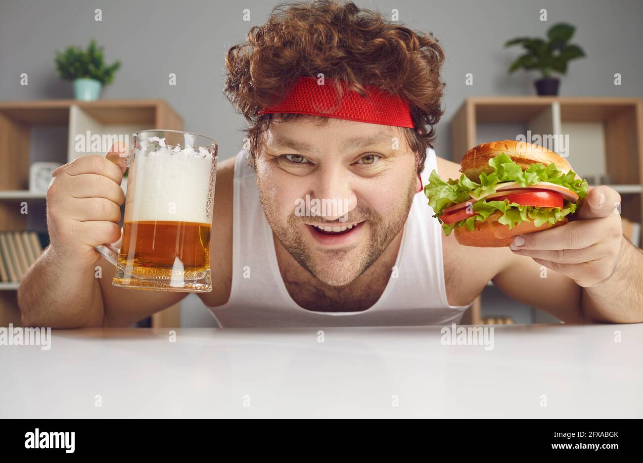 Glücklicher zufriedener Mann genießt es, Hamburger zu essen und Bier aus der Nähe zu trinken Hochformat Stockfoto