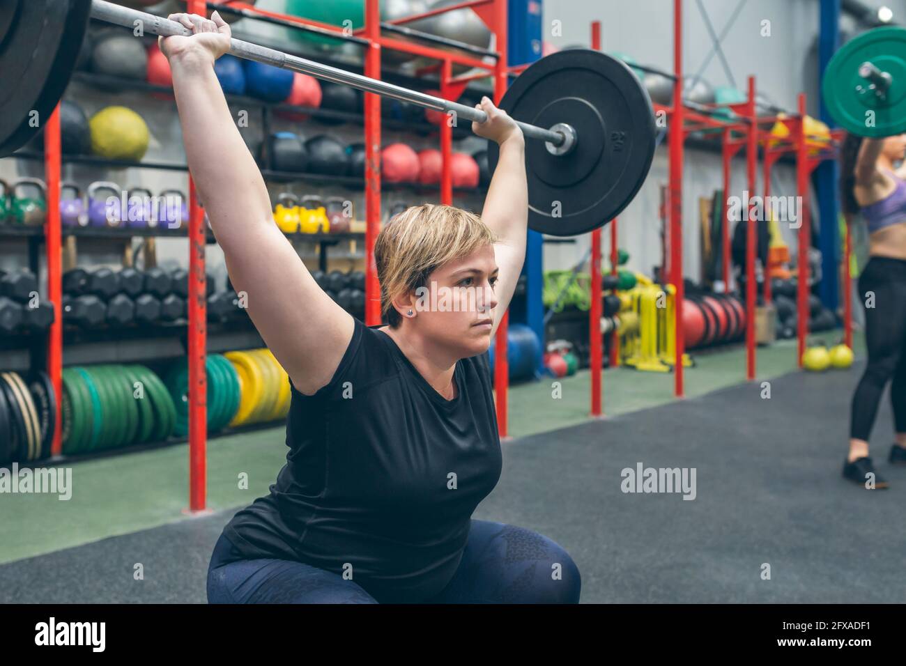 Frau übt Gewichtheben in der Turnhalle Stockfoto