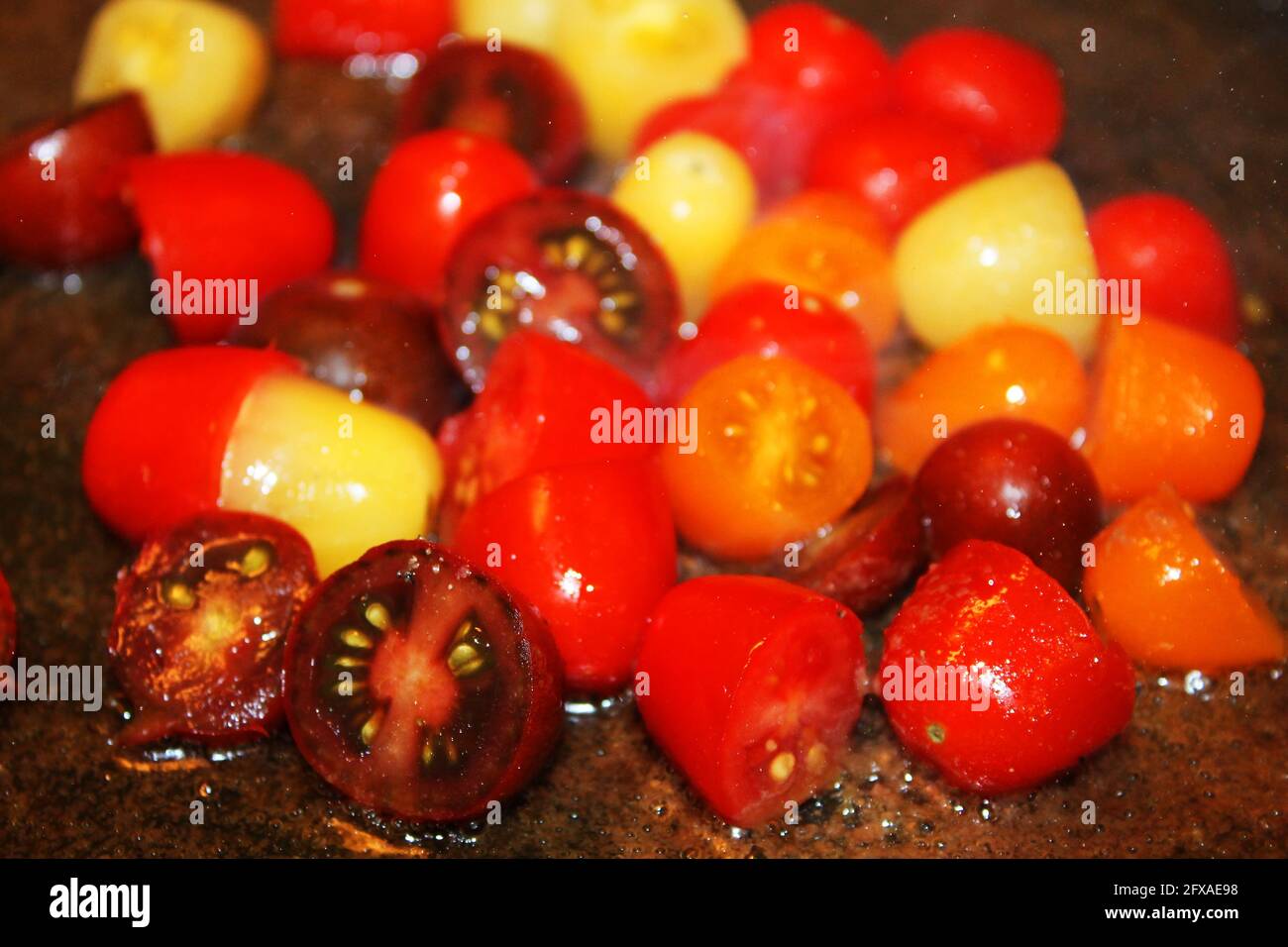 Nahaufnahme von bunten Kirschtomaten, die in Öl gebraten werden. Stockfoto