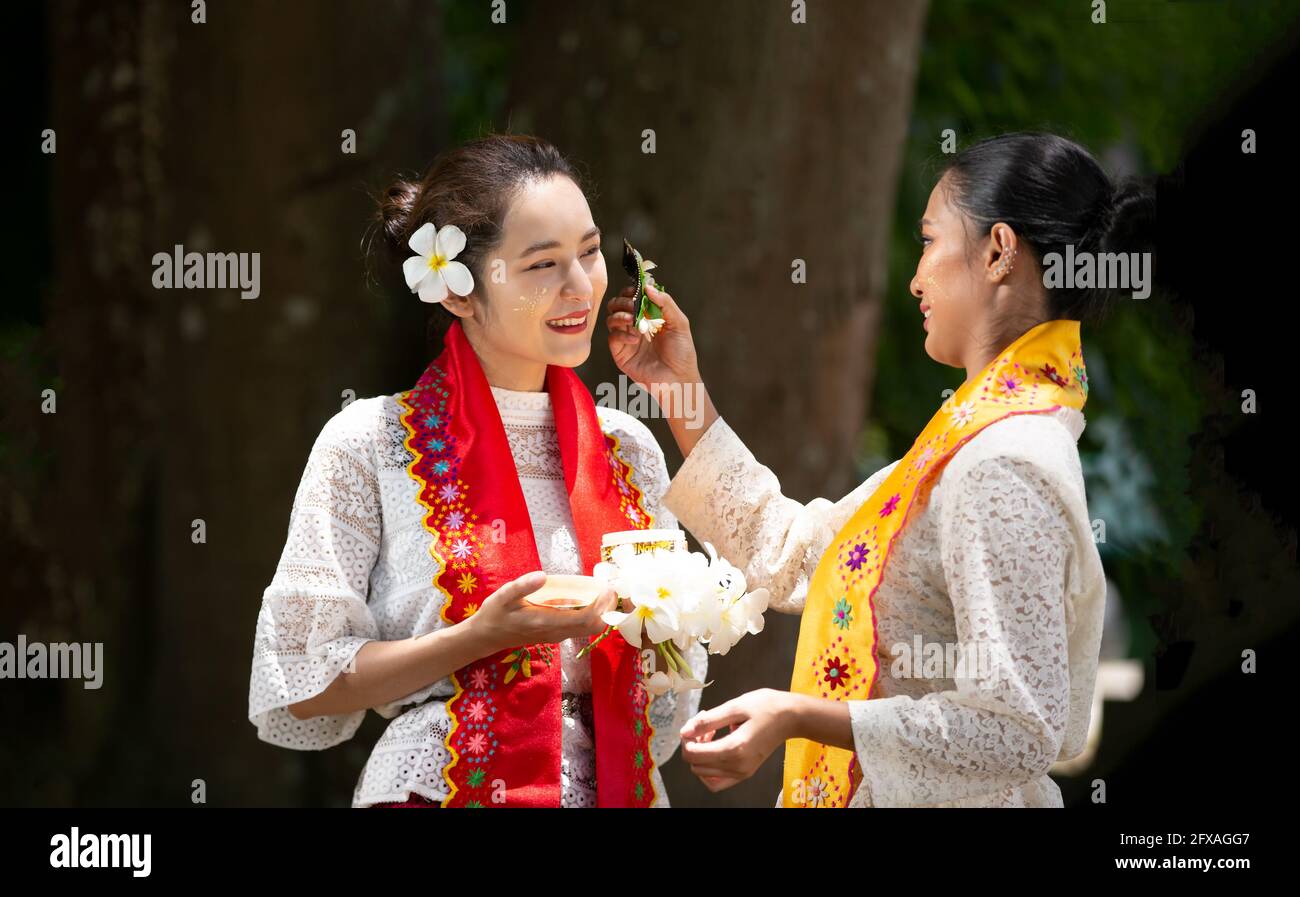 Porträt einer zwei jungen Frau aus Myanmar in einem traditionellen einladenden Kleid und Geste mit Blume . Stockfoto