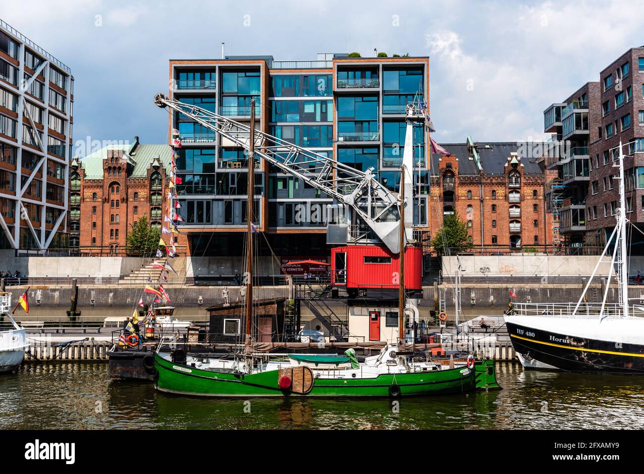 Hamburg, Deutschland - 7. August 2019: Stadtbild des Sandtorhafenkanals mit Schiffen, die am Hafen festgemacht sind, und luxuriösen Wohnhäusern. Sonniger Tag Stockfoto