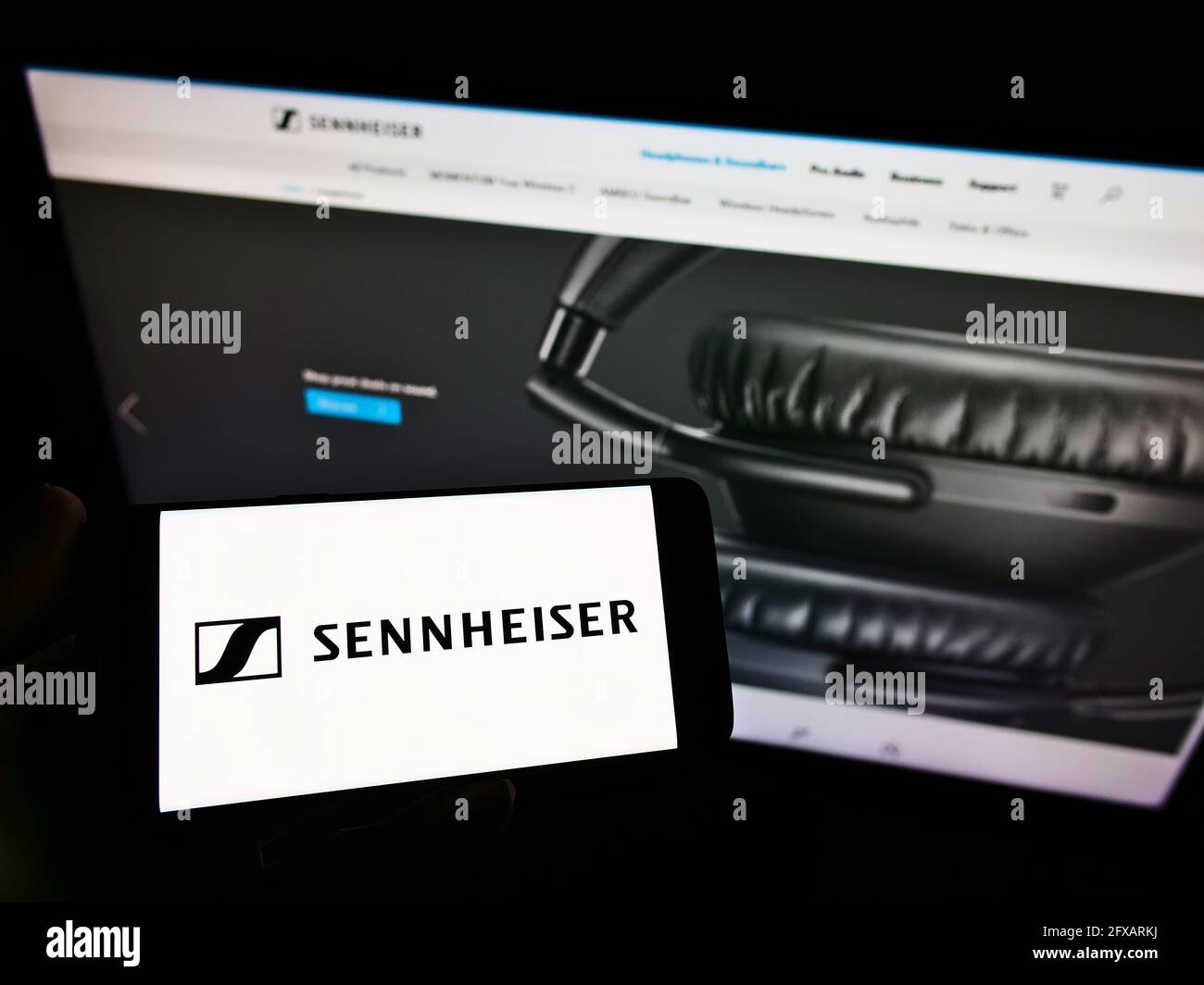 Person, die das Smartphone mit dem Logo des deutschen Audiounternehmens Sennheiser electronic GmbH Co. Kg auf dem Bildschirm vor der Website hält. Konzentrieren Sie sich auf die Telefonanzeige. Stockfoto