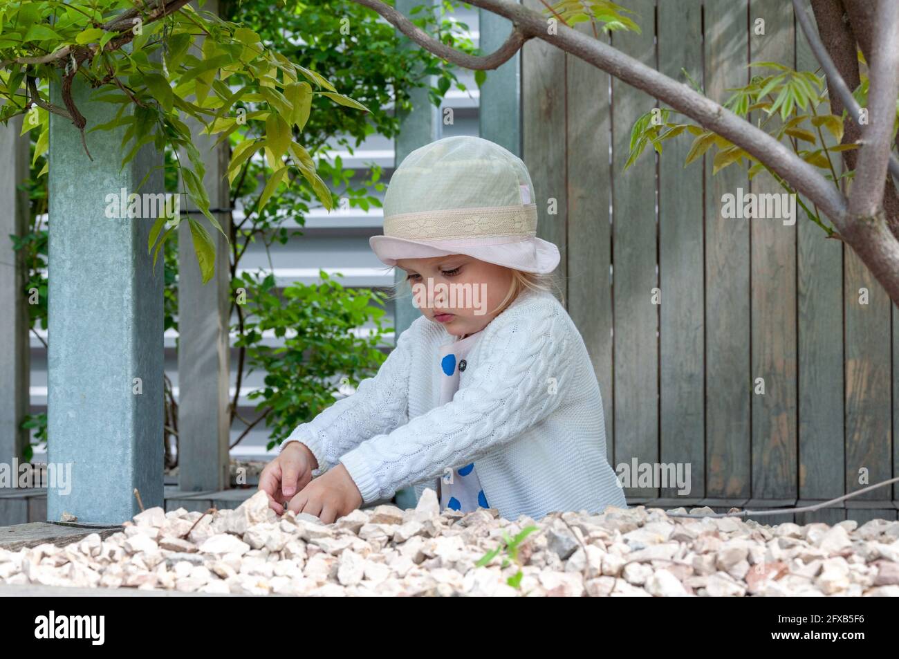 Baby Girl Sammelt Steine Im Garten. Kreative Outdoor-Aktivitäten für Kinder Stockfoto