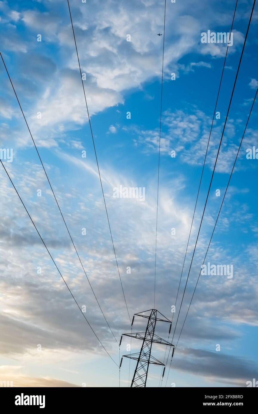 Strommast und Kabel gegen eine blaue bewölkt und hell Sky liefert häuslichen Strom für den grünen Energiebedarf an die Haushalte Stockfoto