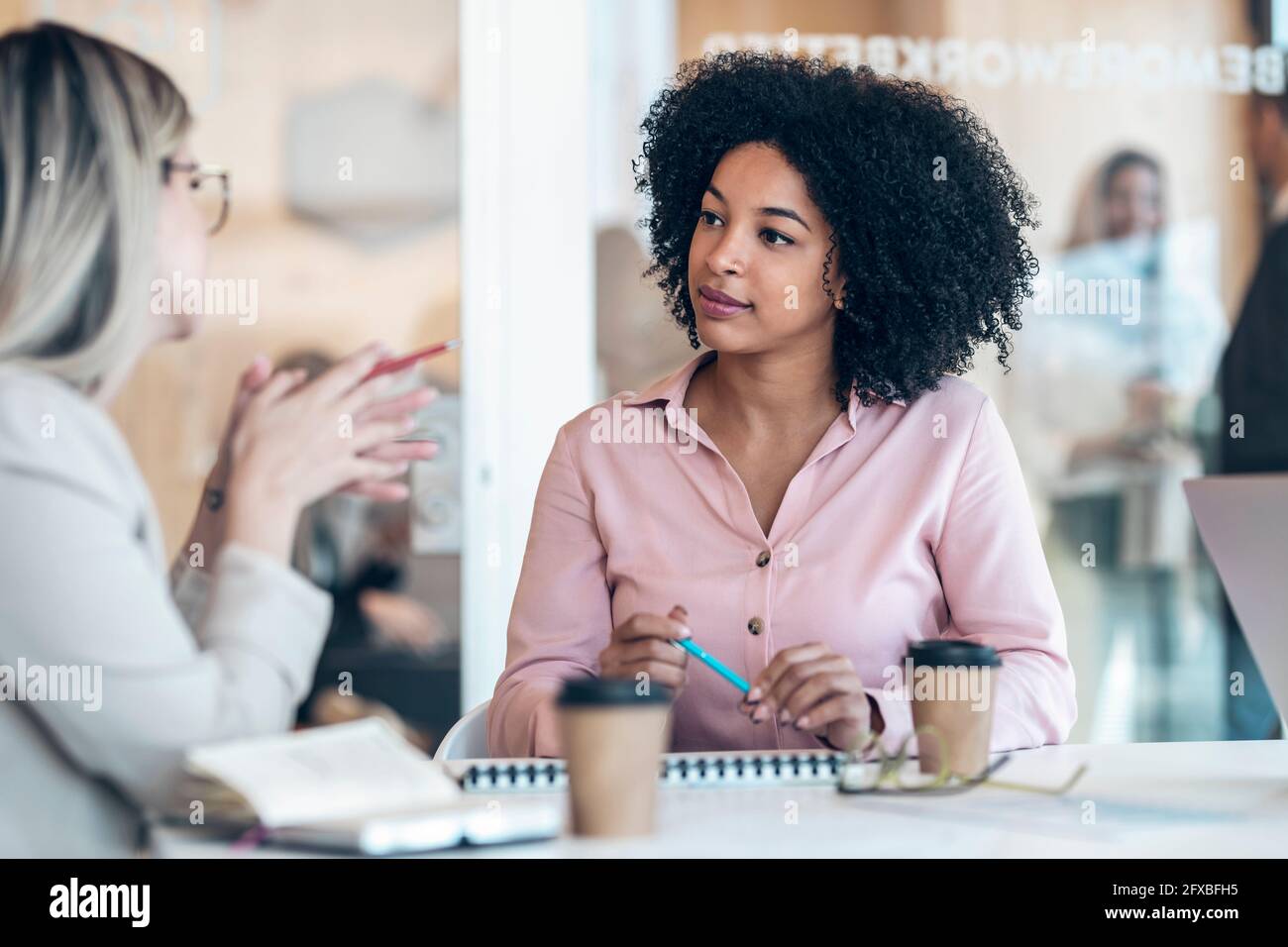 Weibliche Fachleute diskutieren am Schreibtisch im Büro Stockfoto