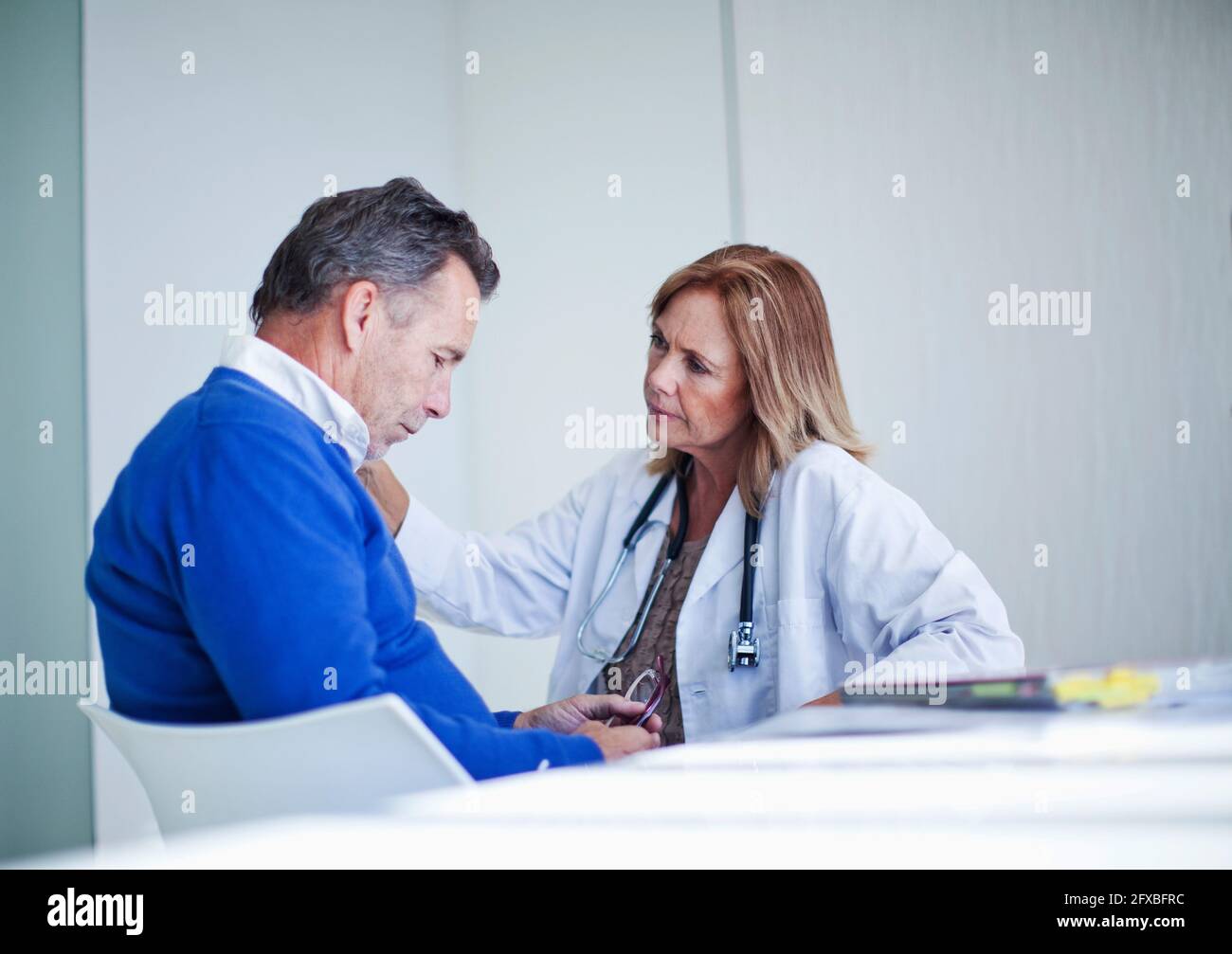 Leitende Ärztin zur Beruhigung des älteren männlichen Patienten Stockfoto