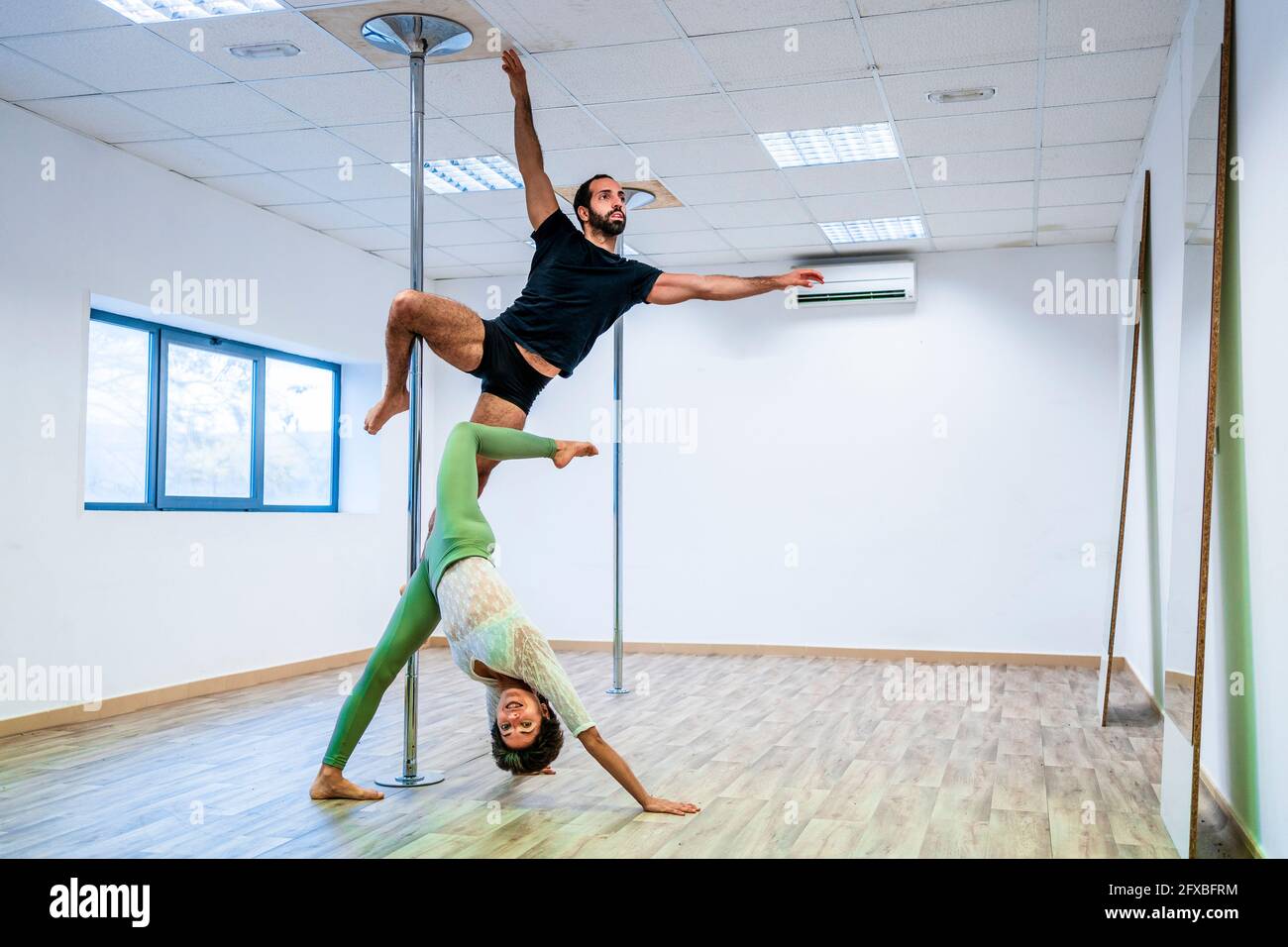 Männliche und weibliche Tänzer dehnen sich während des Übens auf der Rute im Tanzstudio Stockfoto