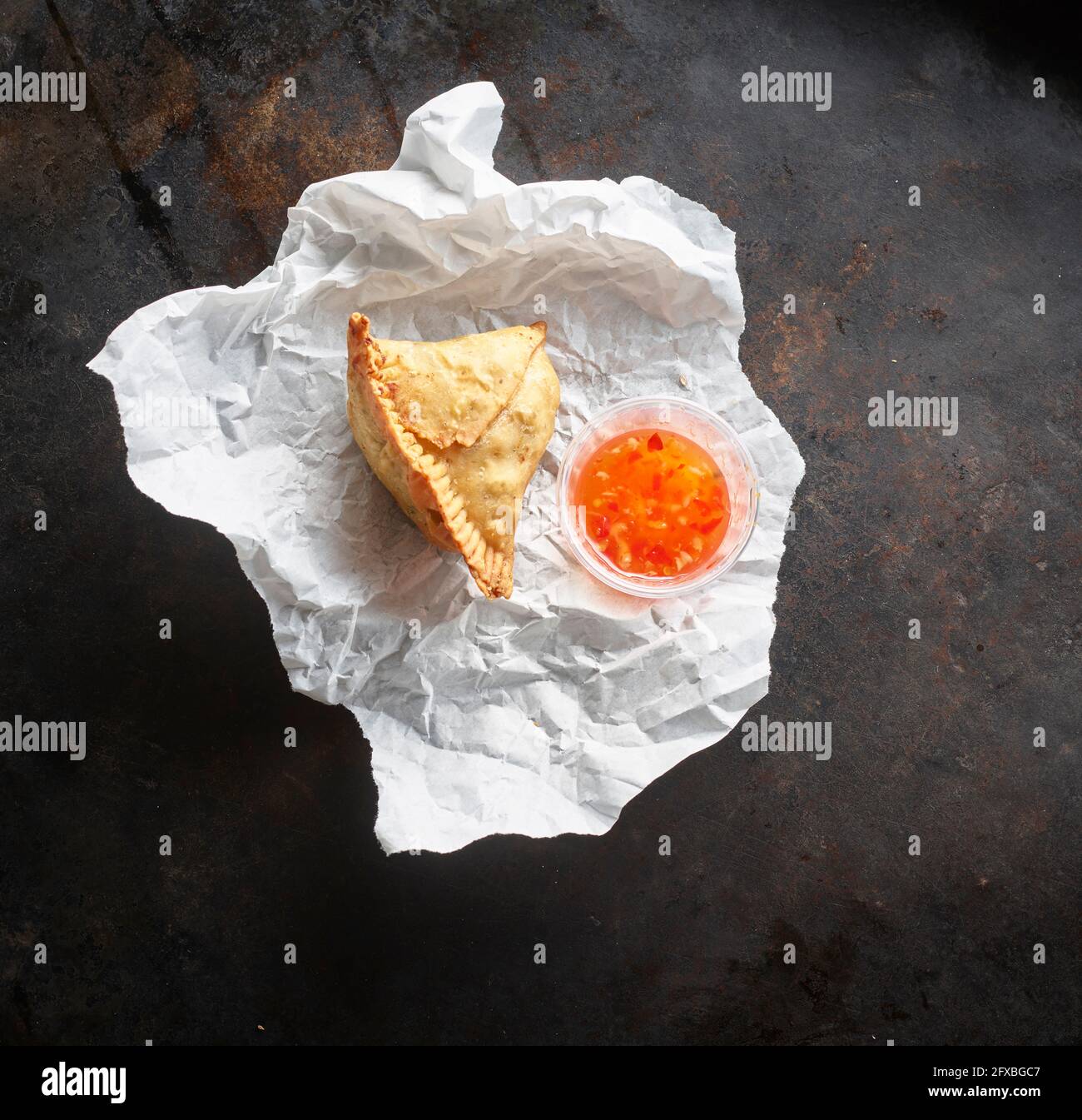 Studioaufnahme des Samosa-Knödlings und einer Schüssel mit Chilisauce auf Papierserviette Stockfoto