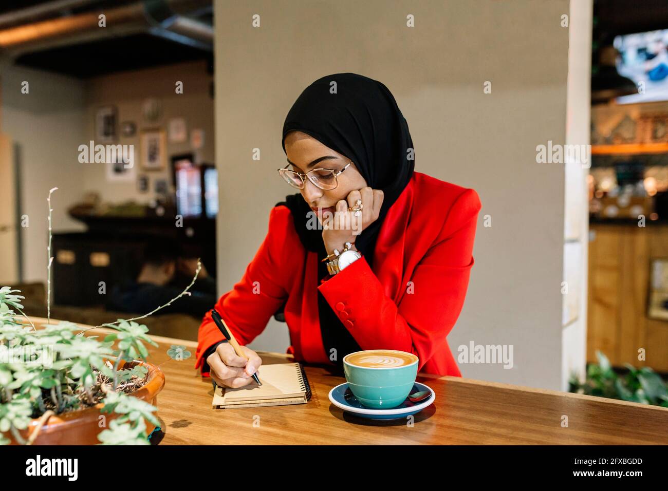 Junge Geschäftsfrau, die im Café Tagebuch schreibt Stockfoto