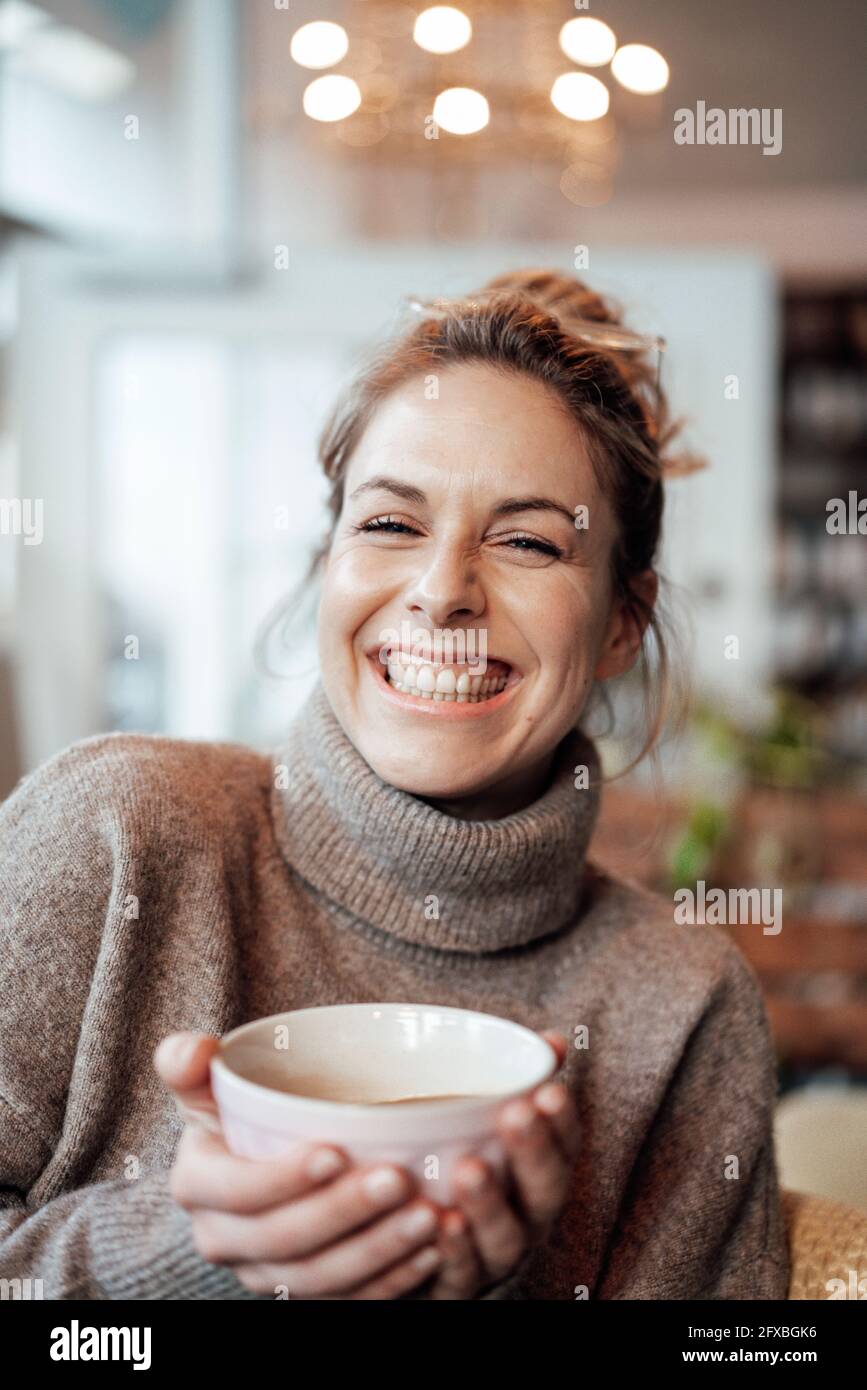 Eine fröhliche Frau hält eine Schüssel im Café Stockfoto