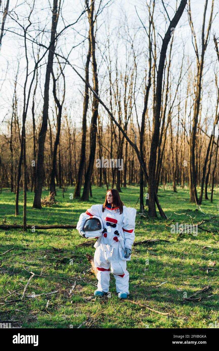 Astronautin mit Weltraumhelm im Wald Stockfoto