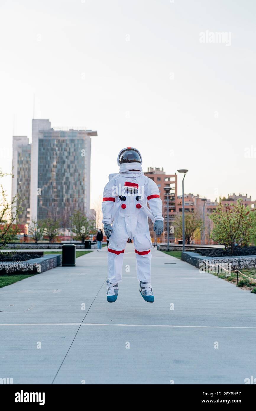 Männlicher Astronaut, der im öffentlichen Park springt Stockfoto