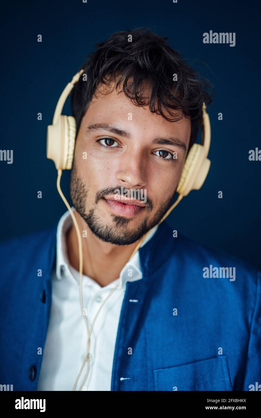 Junger Mann mit Kopfhörern auf blauem Hintergrund Stockfoto